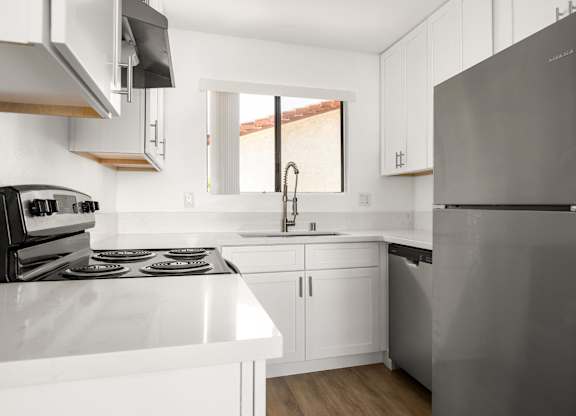 A modern kitchen with a stainless steel refrigerator and white countertops.