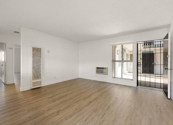 A spacious room with wooden floors and white walls.