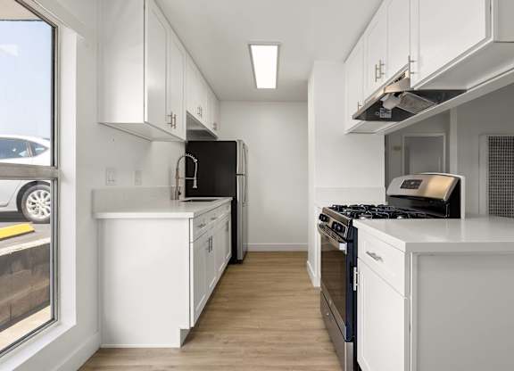 A modern kitchen with white cabinets and black appliances.