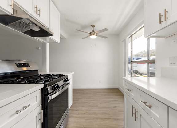 A white kitchen with a black stove top oven.