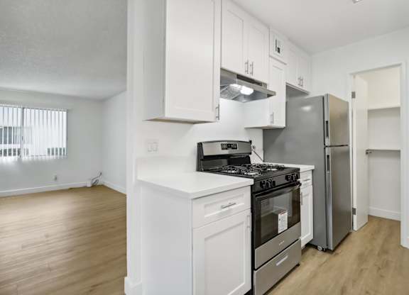A white kitchen with a stove, oven, and refrigerator.