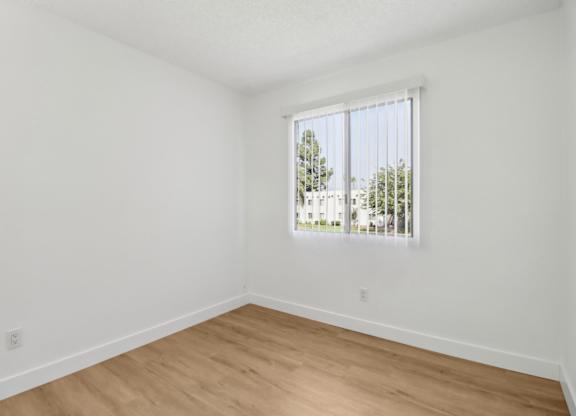 A room with a window and wooden flooring.