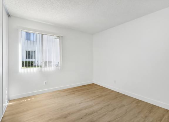 A room with a window and wooden flooring.