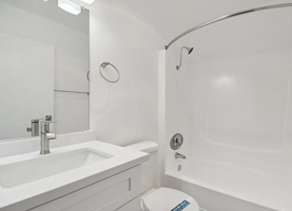 A white bathroom with a toilet, sink, and bathtub.