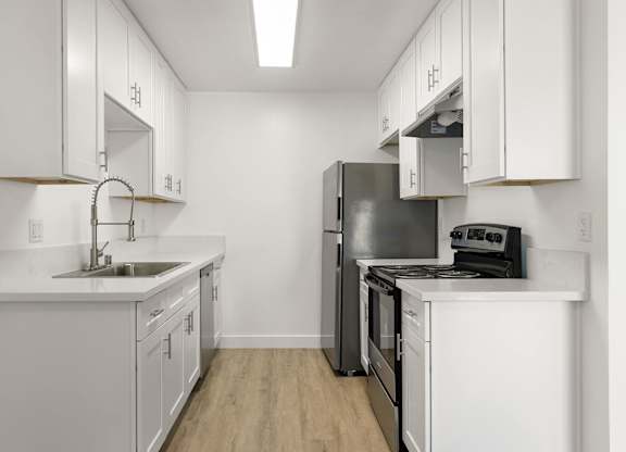 A kitchen with white cabinets and a black refrigerator.