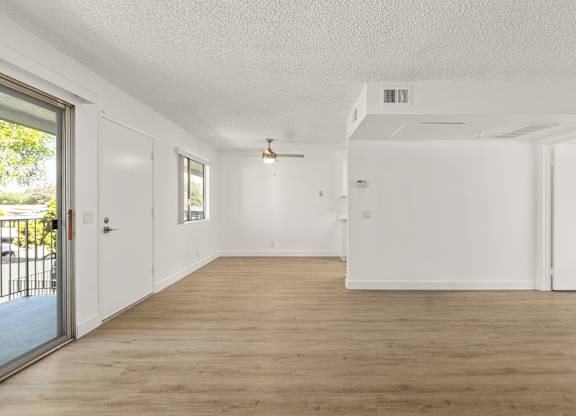 A spacious room with wooden flooring and white walls.