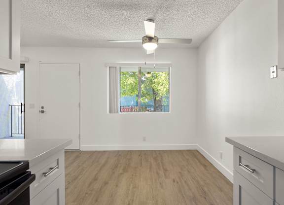 A kitchen with white cabinets and a window with a view of trees.