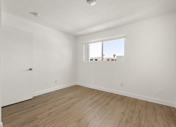 Empty room with a window and wooden flooring.
