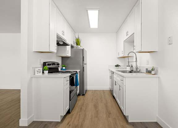 A kitchen with white cabinets and a wooden floor.