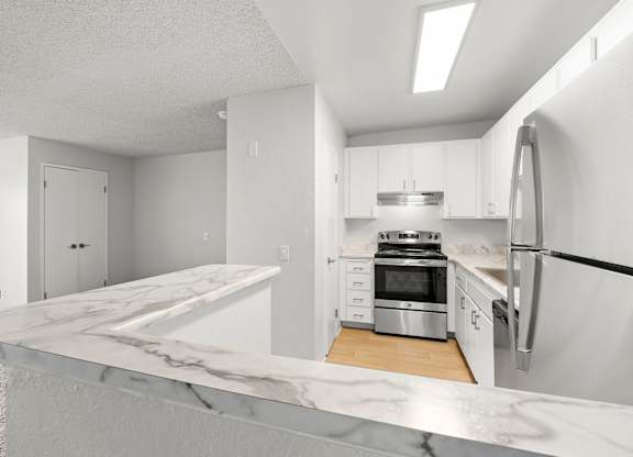 A modern kitchen with a marble countertop and stainless steel appliances.