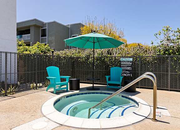 A small pool with a blue striped border and a metal fence surrounding it.