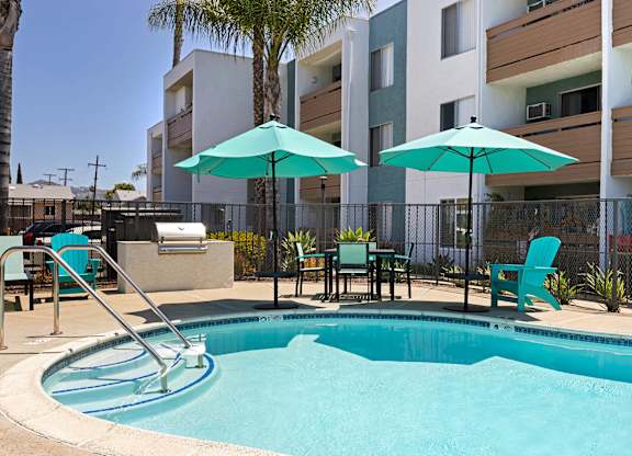 A pool with a slide and chairs with umbrellas.