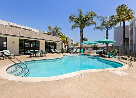 A swimming pool surrounded by chairs and umbrellas.