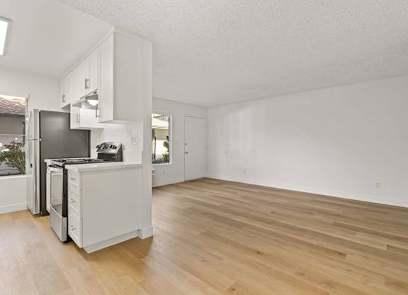 A kitchen with white cabinets and a wooden floor.