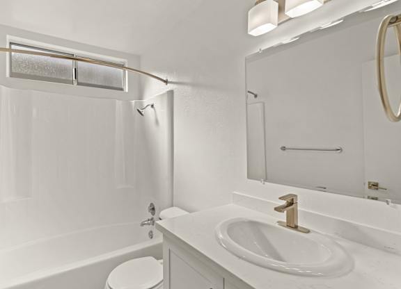 A white bathroom with a toilet, sink, and tub.