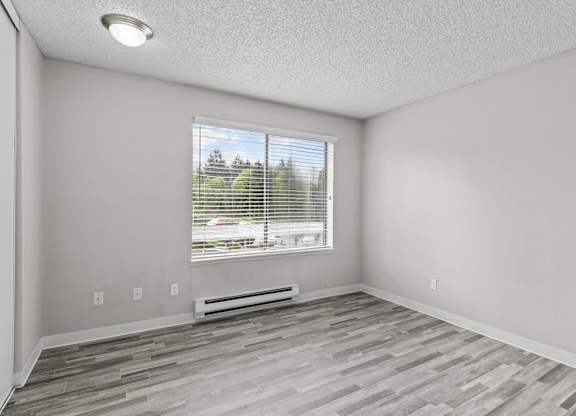 A room with a window and a wooden floor.