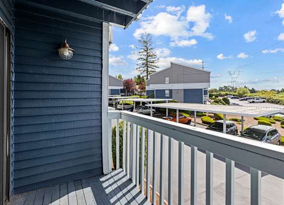 A balcony with a view of a parking lot and a building.