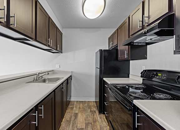 A kitchen with dark wood cabinets and black appliances.