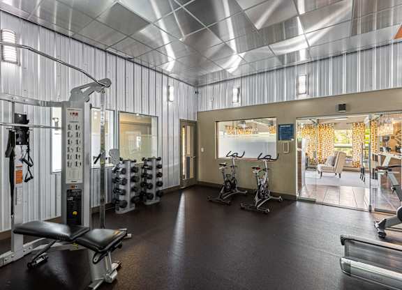 A gym with a variety of equipment including weights and cardio machines.