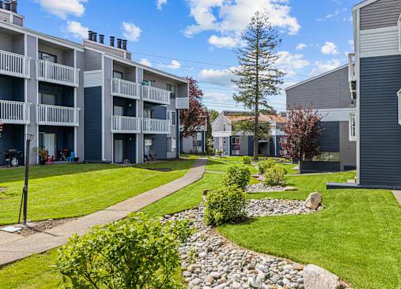 Apartment complex with a grassy area and a stone path.