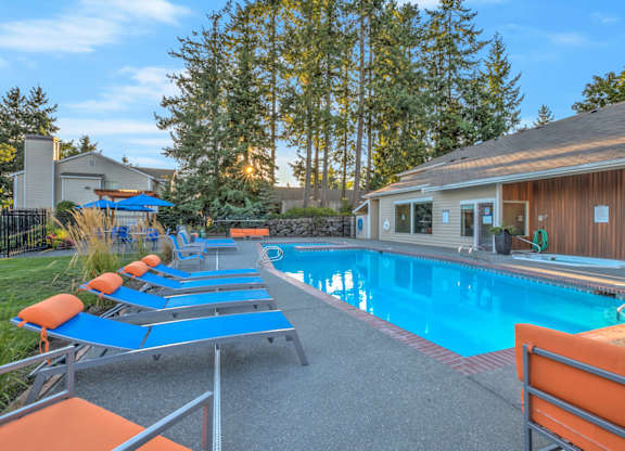 A pool with sun loungers and a building in the background.
