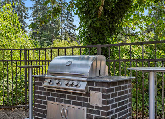 A charcoal grill is on a patio with a table and a railing.