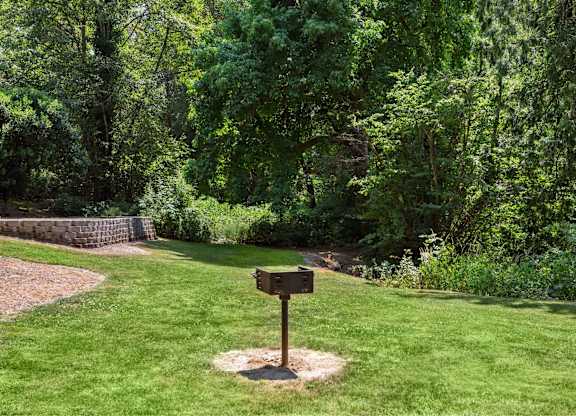 A signpost stands in a grassy area with a forest in the background.