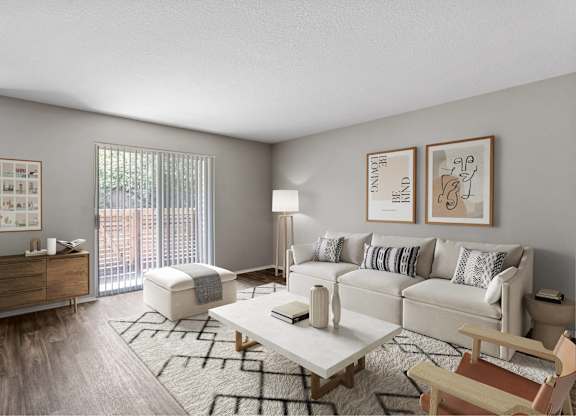 A living room with a white couch, a wooden chair, a coffee table, and pictures on the wall.