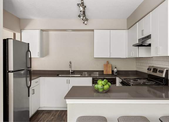 A kitchen with a refrigerator, stove, and sink.