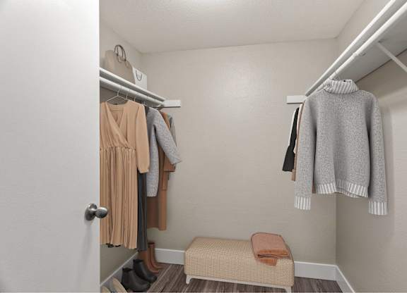 A small closet with a bench and clothes hanging.