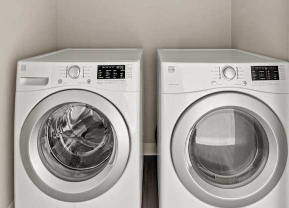 Two white front loading washing machines in a laundry room.