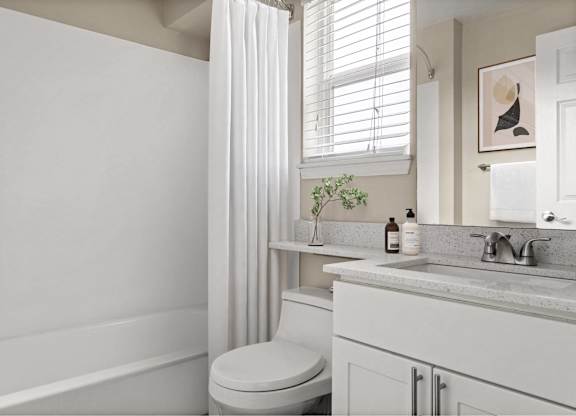 A white bathroom with a toilet, sink, and bathtub.