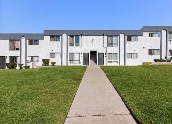 A long white building with a walkway in front.