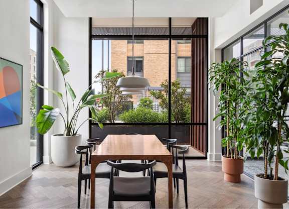 A dining room with a table and chairs and a potted plant.