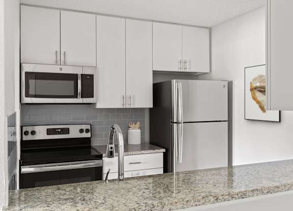 A modern kitchen with a granite countertop and stainless steel appliances.