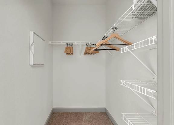 A white closet with a brown hanger and a white wall.