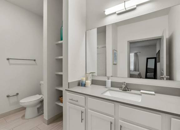 A white bathroom with a toilet, sink, and mirror.
