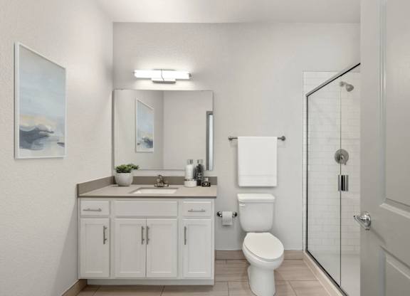 A white bathroom with a toilet, sink, and a mirror.