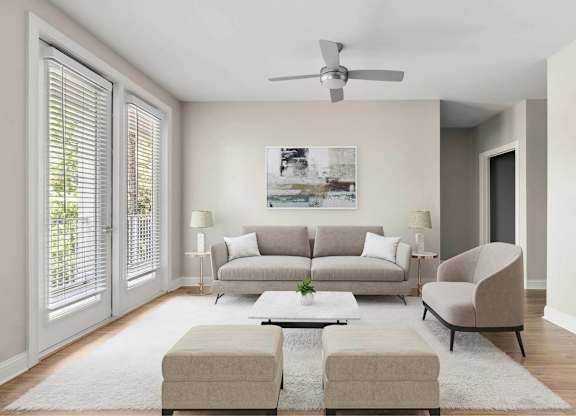 A living room with a grey couch, a white rug, and a ceiling fan.