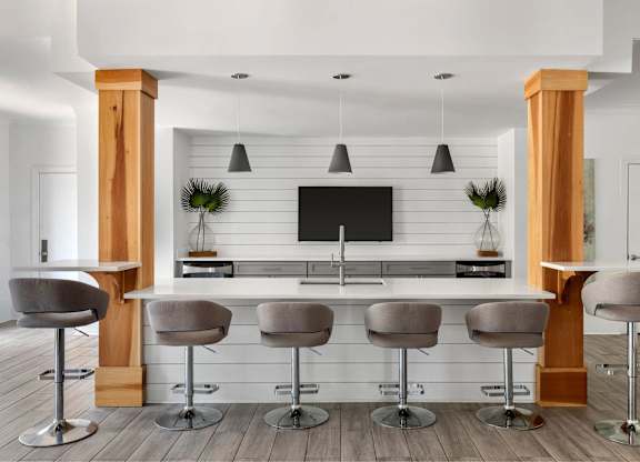 A modern bar area with grey bar stools and a black counter.