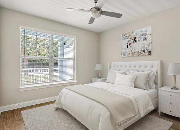 A bedroom with a window and ceiling fan.