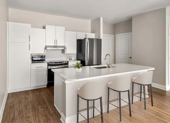 A kitchen with a countertop island and chairs.