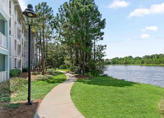 A sidewalk near a pond.