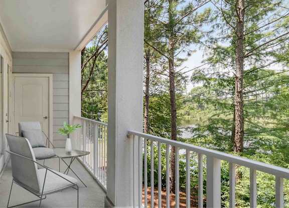 A balcony with chairs facing trees.