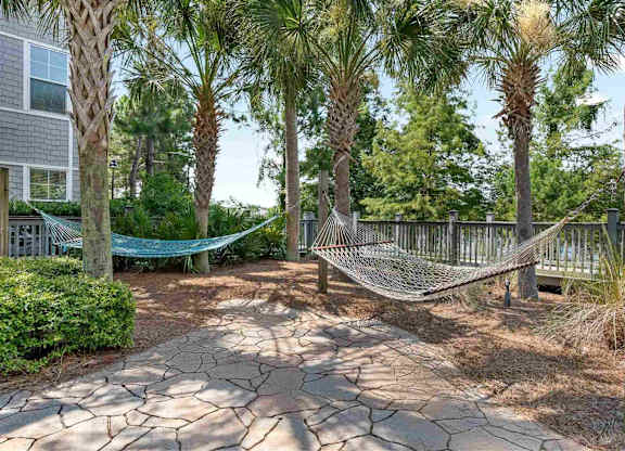 A hammock is strung between two wooden posts in a backyard.