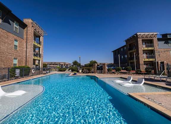 A swimming pool in front of a brick building.