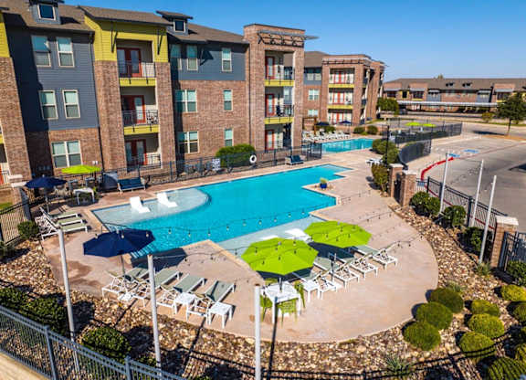 A large swimming pool surrounded by a fence and chairs.