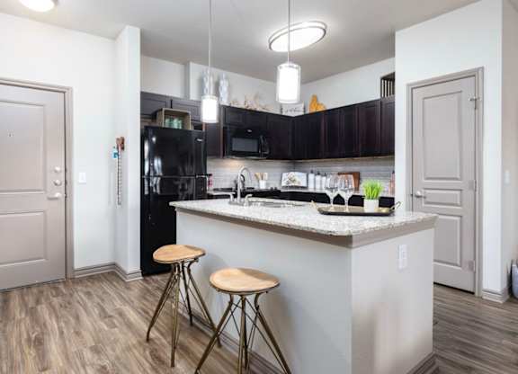 A kitchen with a white island and black appliances.