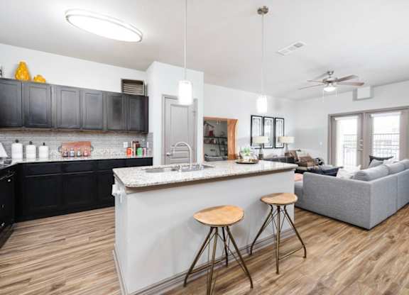 A kitchen with a bar and a couch in the living room.