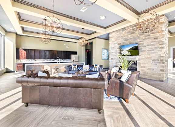 A brown leather sofa sits in a spacious room with a stone pillar and a TV mounted on the wall.